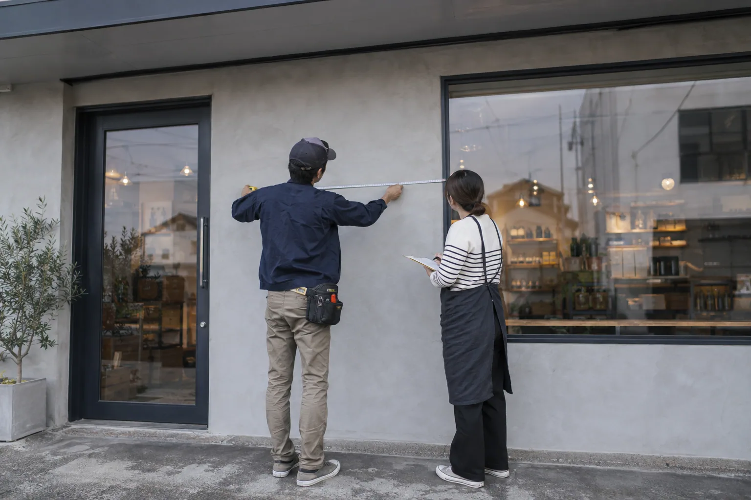 店舗の窓まわりを採寸しながら相談する様子の生成イメージ